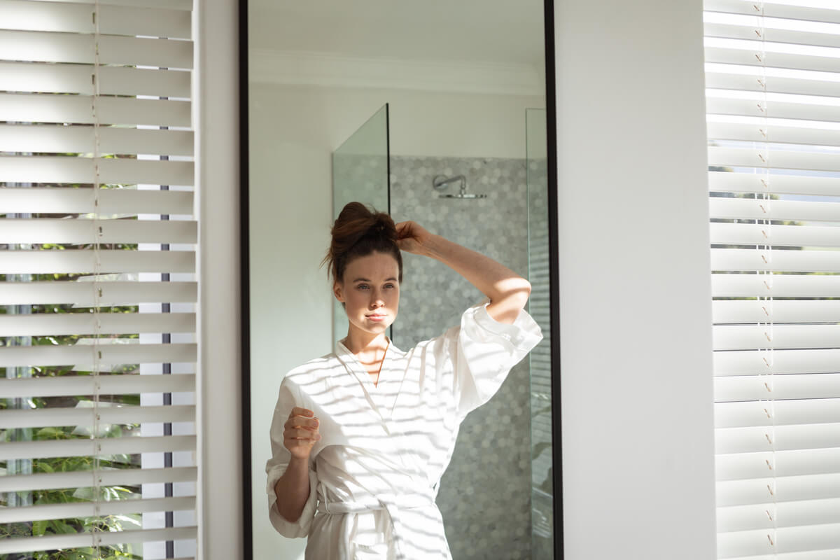 woman stying her hair while looking in the mirror